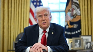 President Donald Trump sits in the Oval Office as he announces tariffs on auto imports.