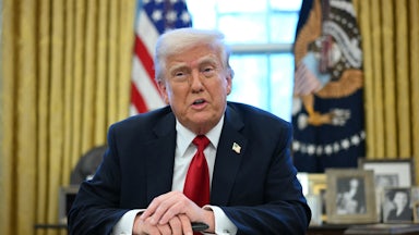 President Donald Trump sits in the Oval Office as he announces tariffs on auto imports.