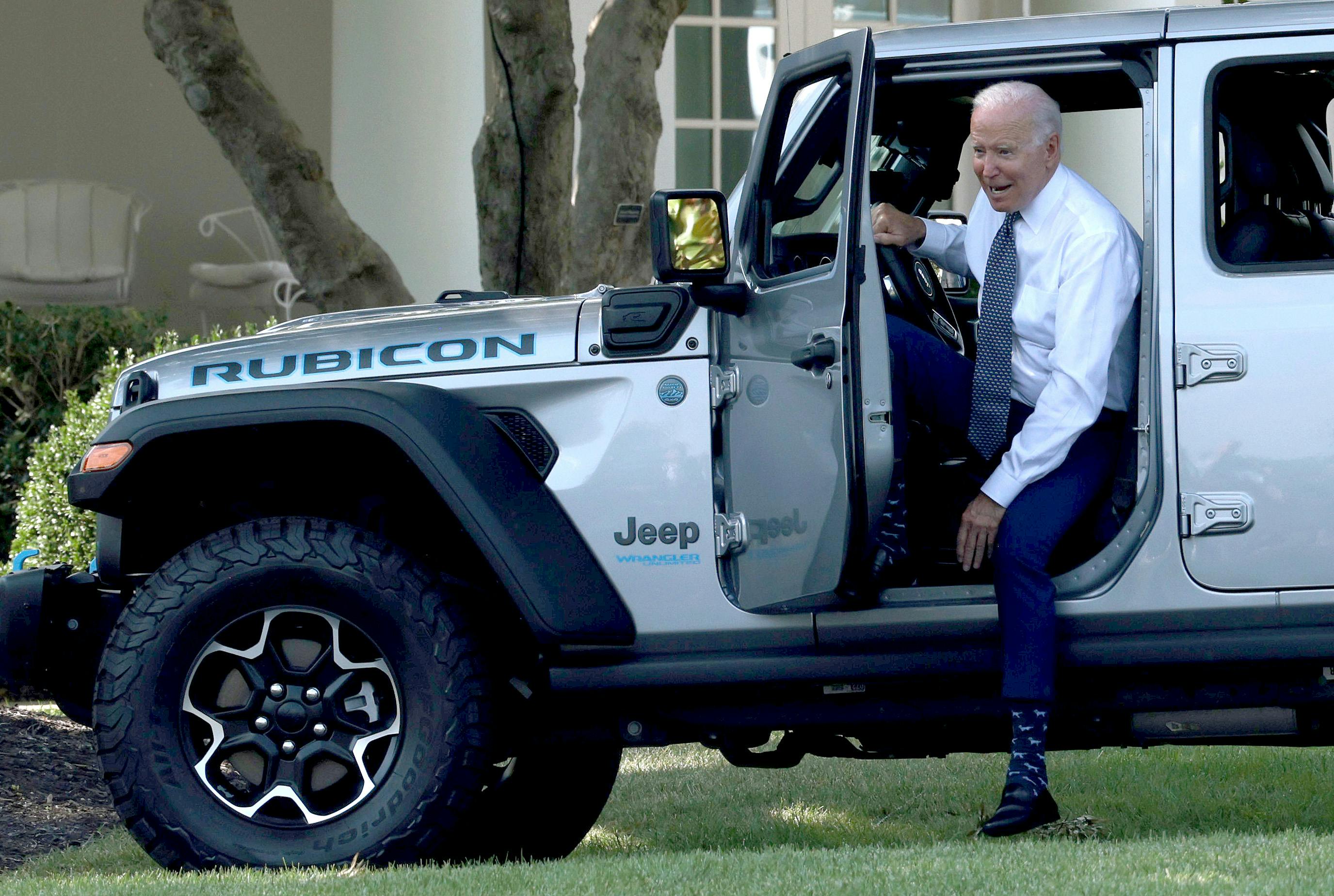 President Biden climbs out of a Jeep.