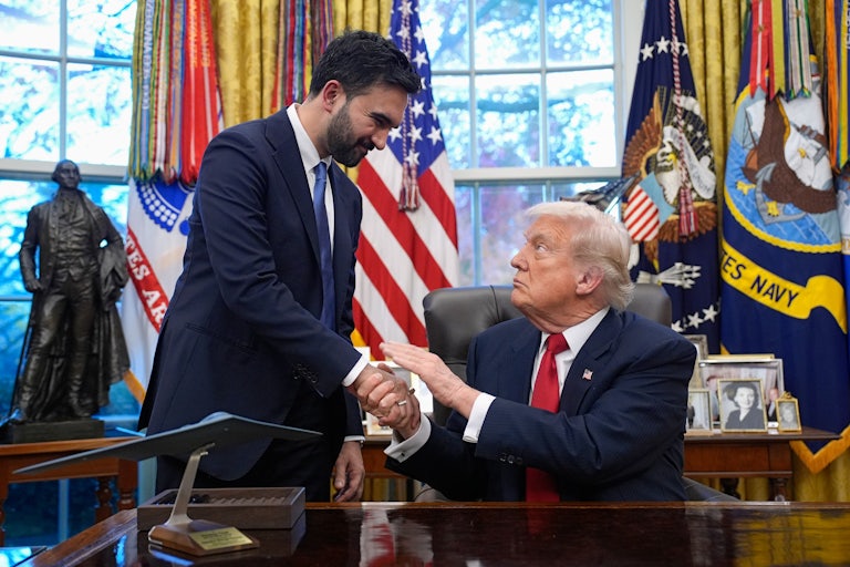 Zohran Mamdani and Donald Trump shake hands. Trump is sitting at his desk in the Oval Office