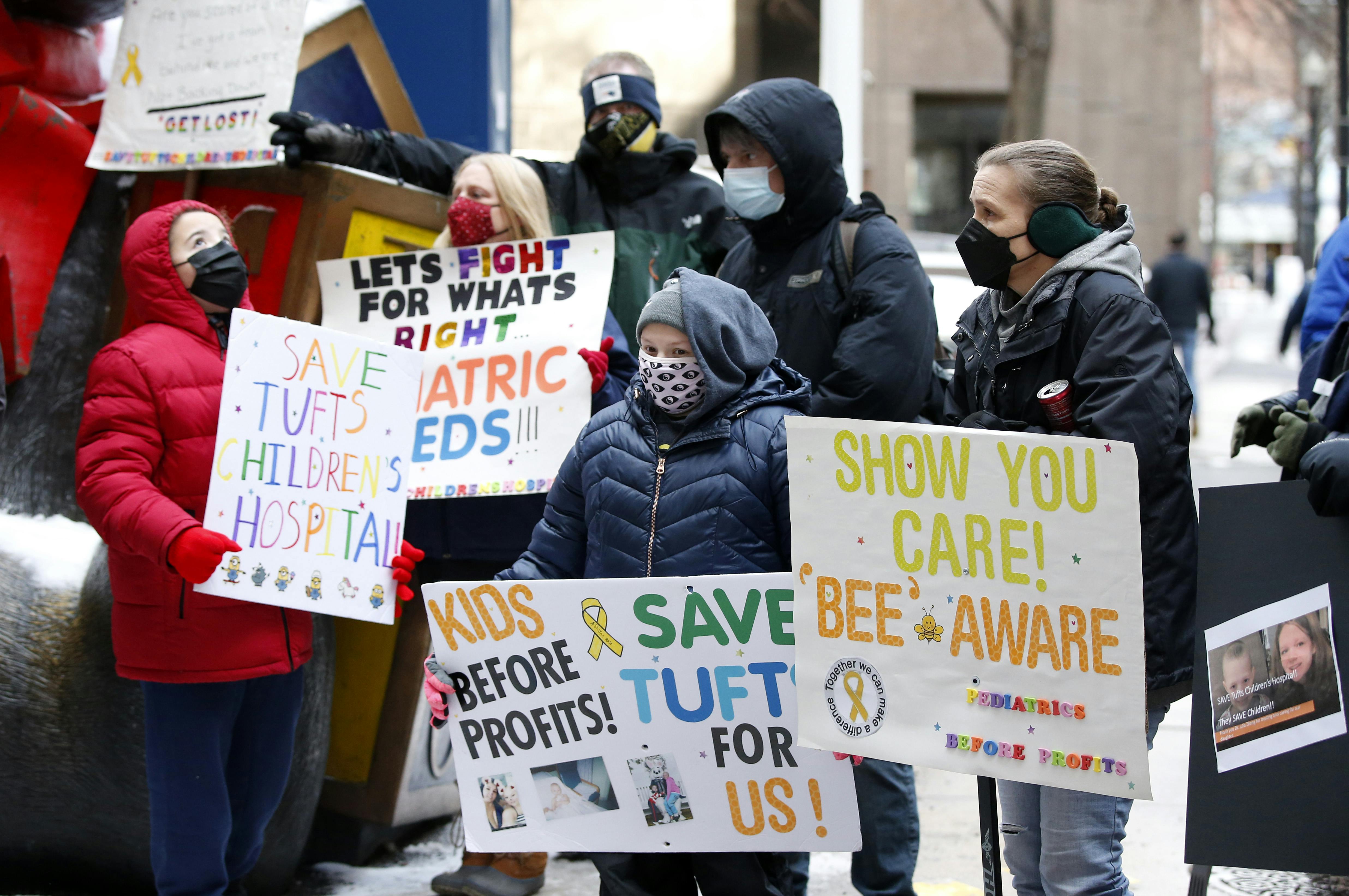 Demonstrators hold signs in support of Tufts Children's Hospital.
