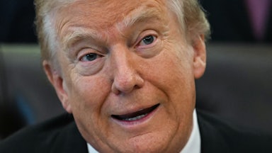 Donald Trump speaks while sitting at his desk in the Oval Office