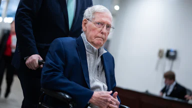 Senator Mitch McConnell is pushed through the U.S. Capitol in a wheelchair.