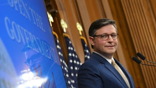 House Speaker Mike Johnson looks to the side and makes a weird face while standing at a podium