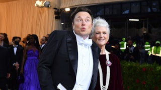 Elon Musk purses his lips and spreads his hands while wearing white tie.
