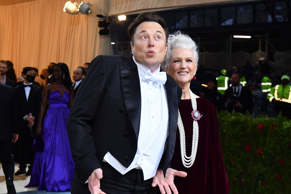 Elon Musk purses his lips and spreads his hands while wearing white tie.