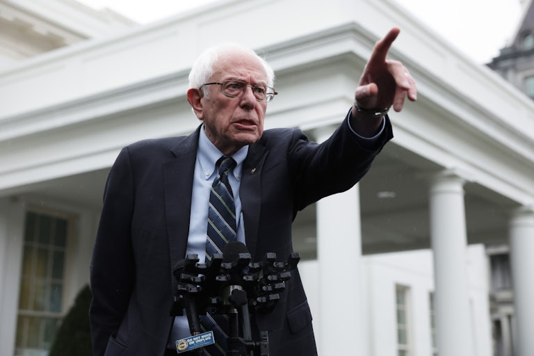 Senator Bernie Sanders speaks at a lectern outside the White House and points to something off screen