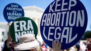 Hands hold signs reading "Keep Abortion Legal" and "ERA Now."