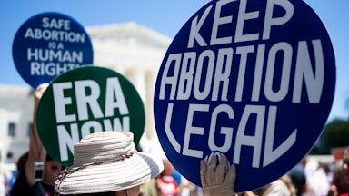 Hands hold signs reading "Keep Abortion Legal" and "ERA Now."