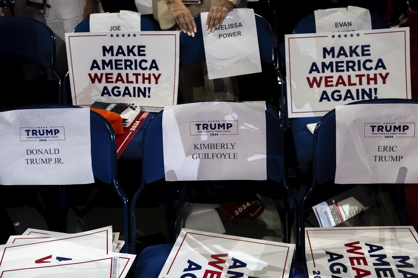 A photograph of chair signs at the republican national convention that include the slogan make america wealthy again