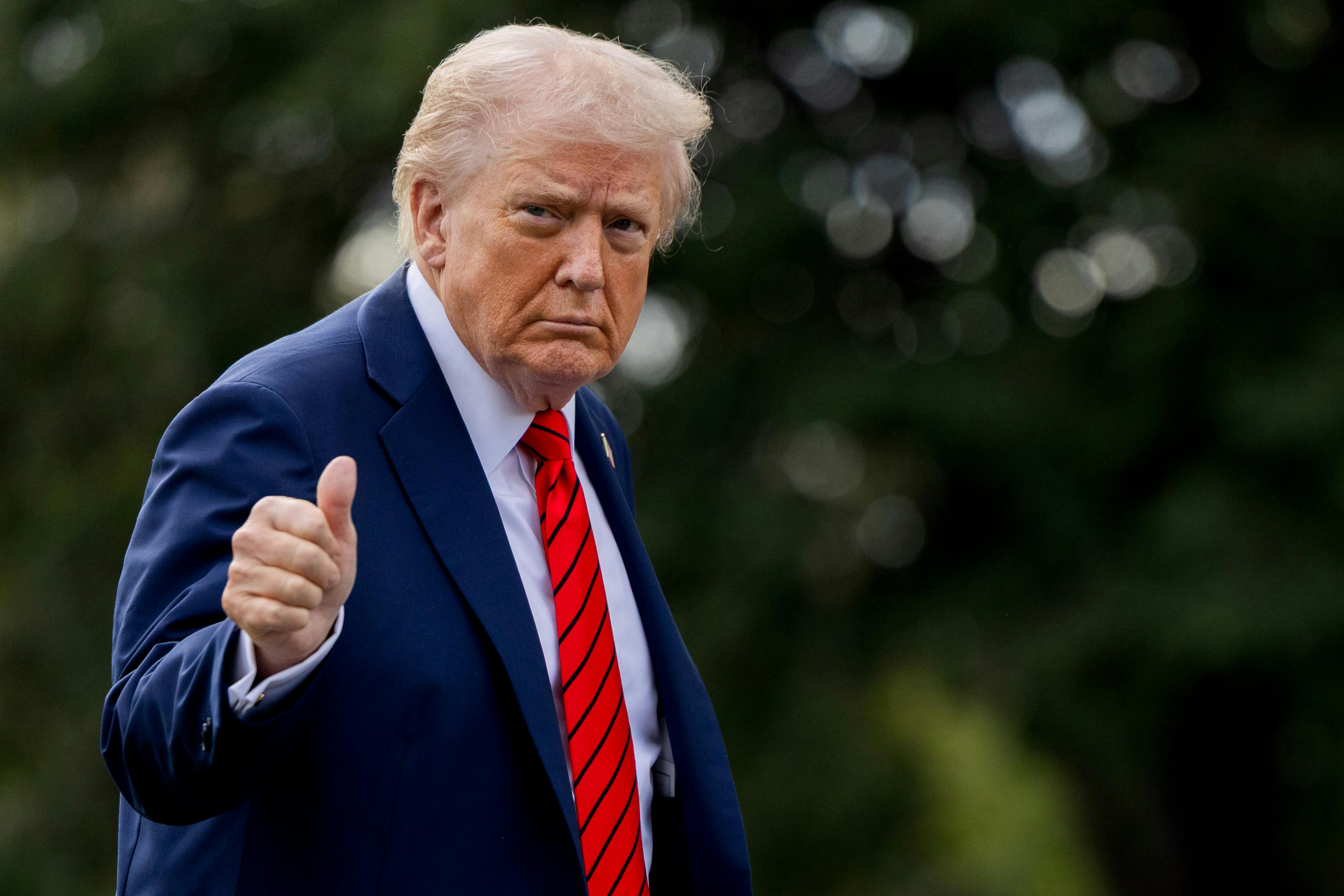 Donald Trump gives a thumbs-up while walking outside the White House