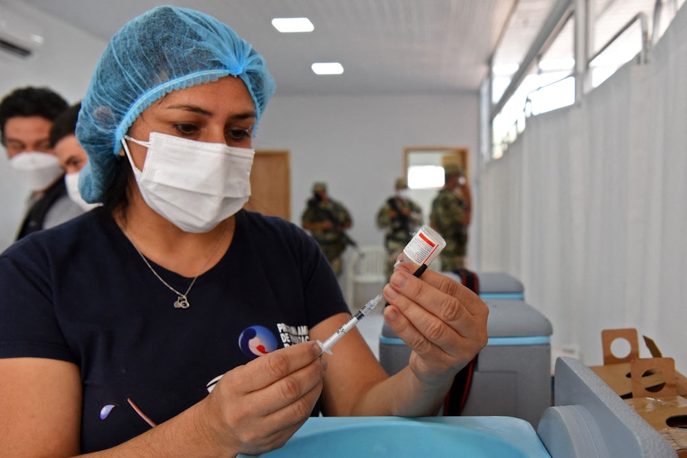 A nurse fills a syringe from a vial.