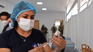 A nurse fills a syringe from a vial.