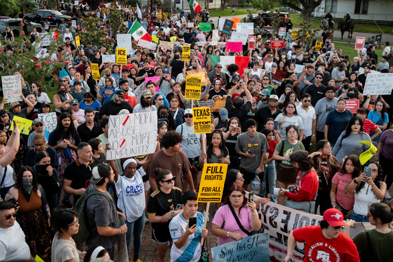 A large group of people People march to honor Mexican immigrant Lorenzo Salgado Araujo, holding signs and the Mexican flag.