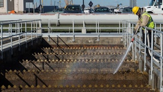 A worker sprays water into a wastewater tank.