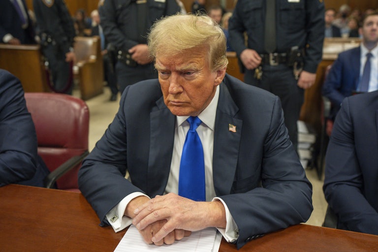 Donald Trump looks down while sitting in court for his hush-money trial