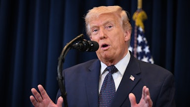 Donald Trump gestures with both hands while speaking at a podium