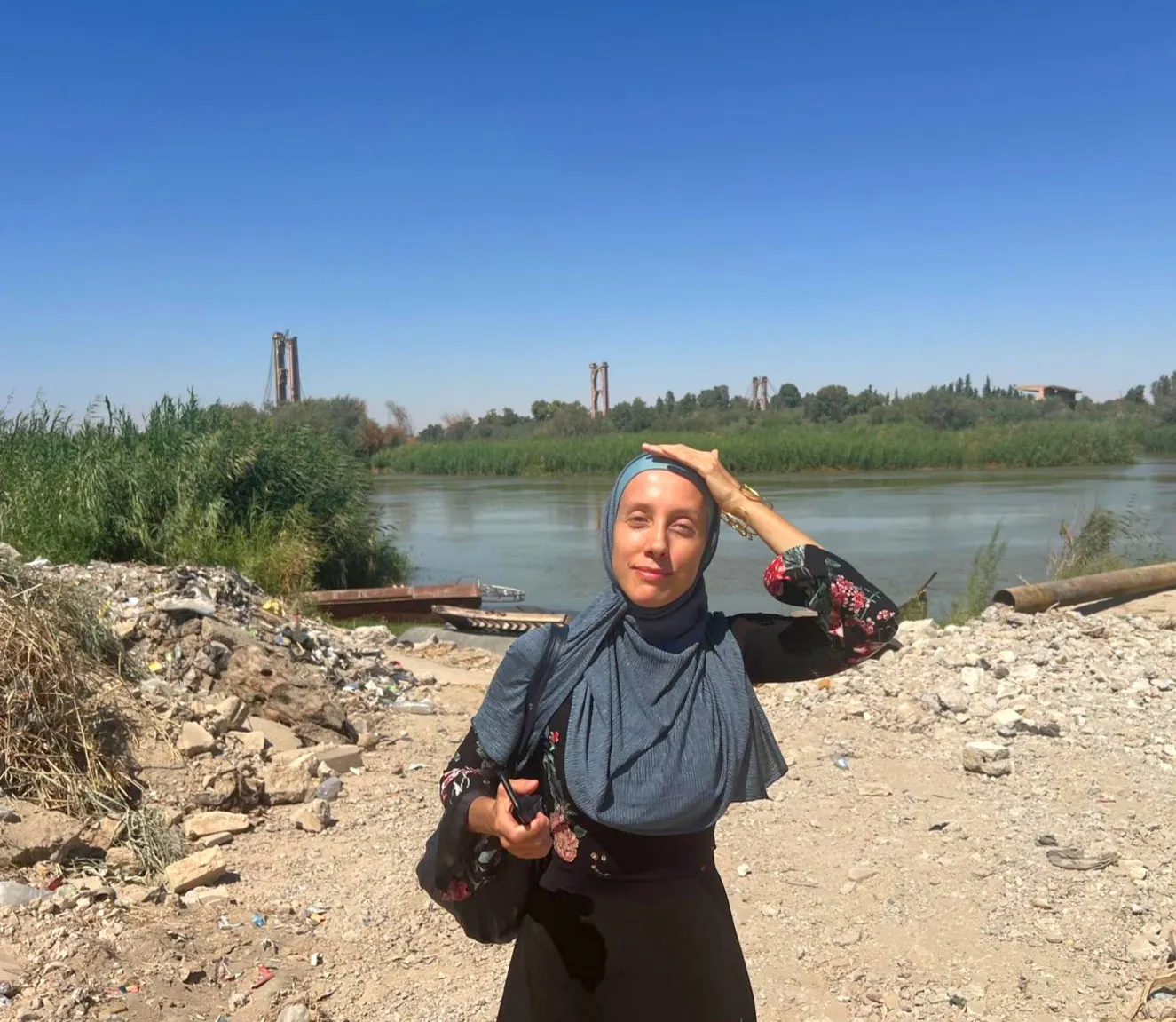 Shelly Kittleson wears a hijab and places her hand on her head as the sun beats down.