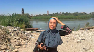 Shelly Kittleson wears a hijab and places her hand on her head as the sun beats down.
