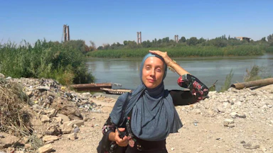 Shelly Kittleson wears a hijab and places her hand on her head as the sun beats down.