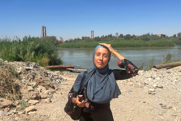 Shelly Kittleson wears a hijab and places her hand on her head as the sun beats down.