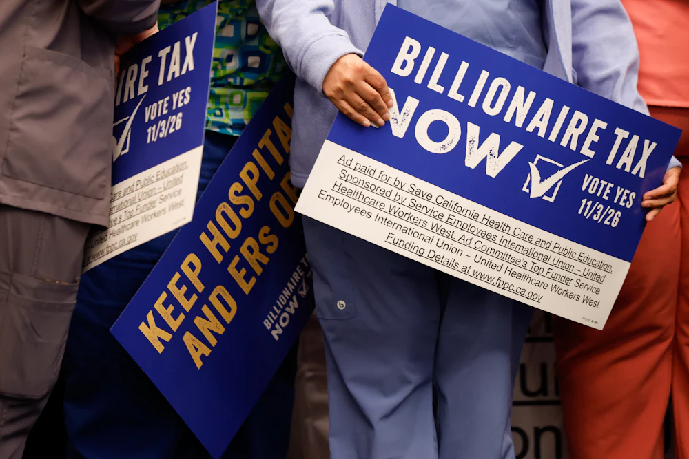 Supporters hold signs advocating for the Billionaire Tax Now coalition during a news conference in Los Angeles, California.