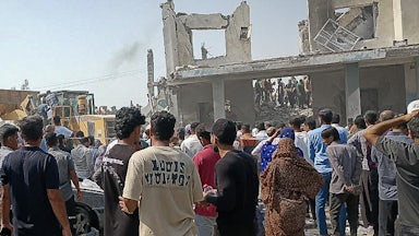 People gather at the destroyed site of a girls' school in Iran