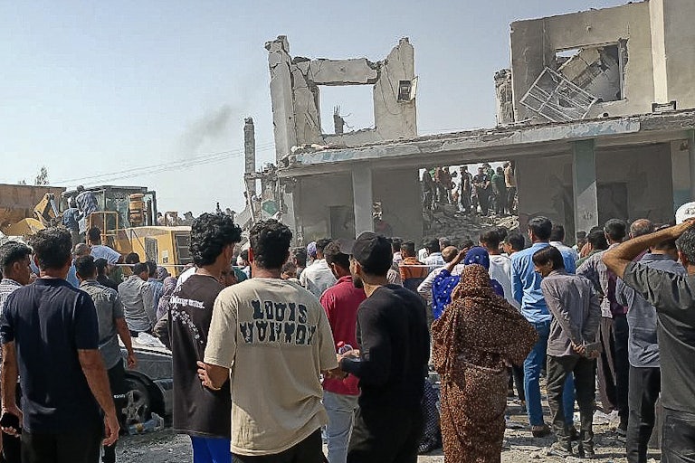 People gather at the destroyed site of a girls' school in Iran