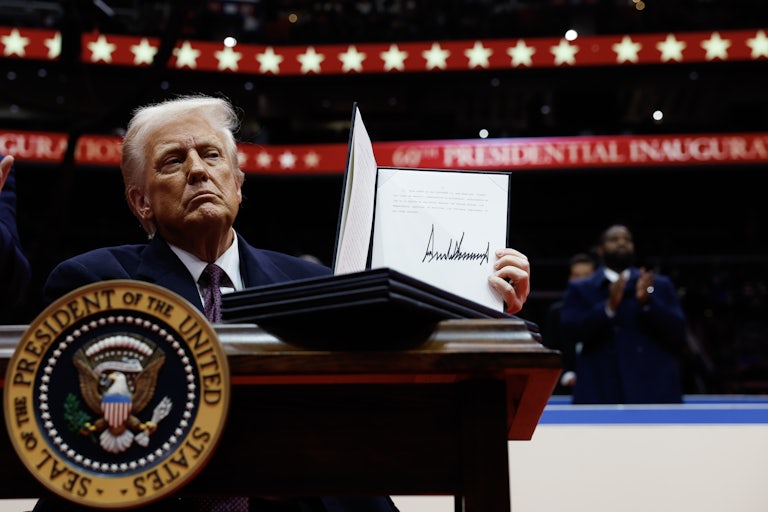 Donald Trump holds up a signed executive order during his inaugural parade