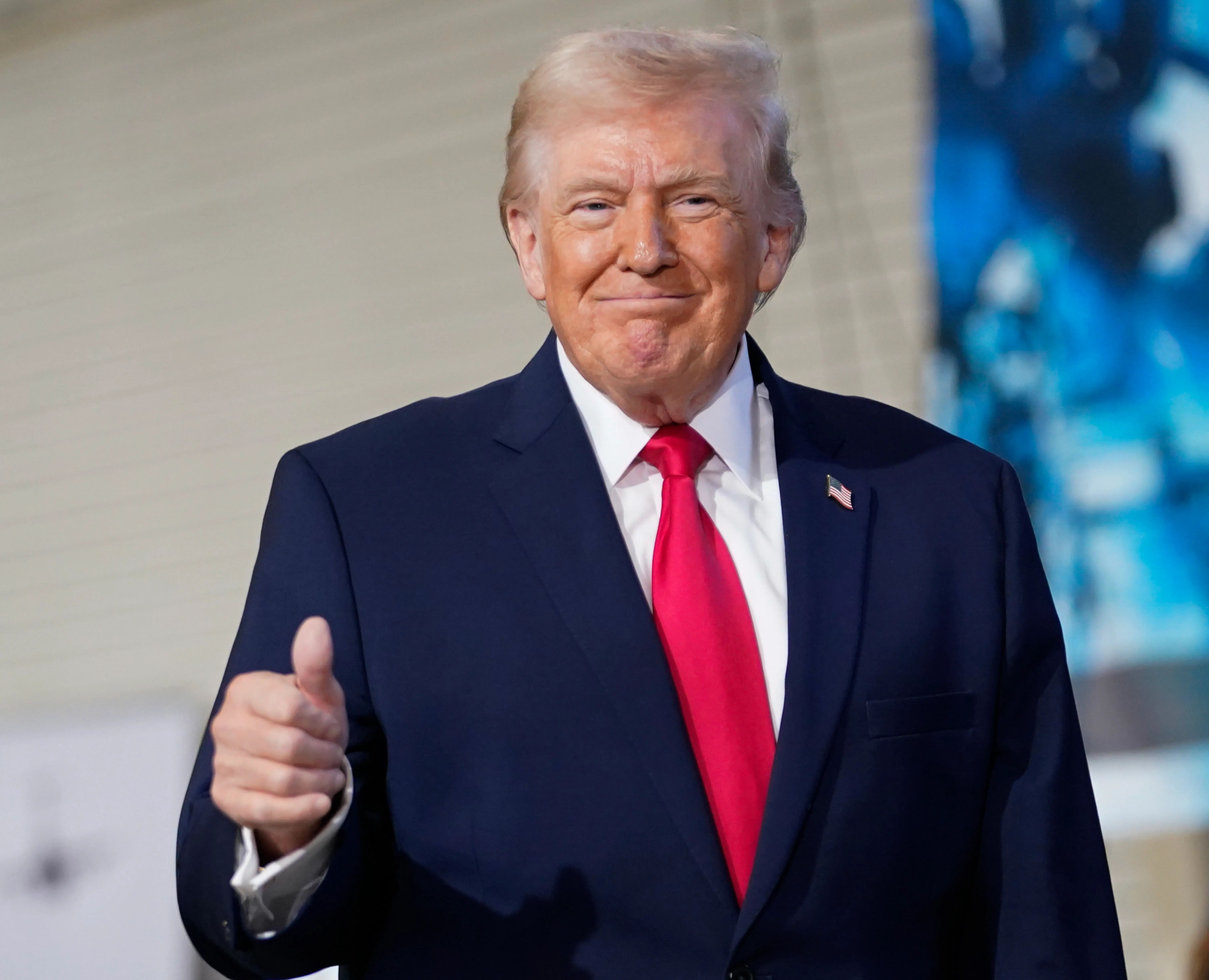 Donald Trump smiles while making a "thumbs up" sign.