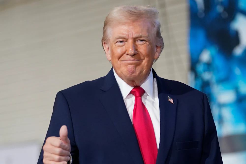 Donald Trump smiles while making a "thumbs up" sign.