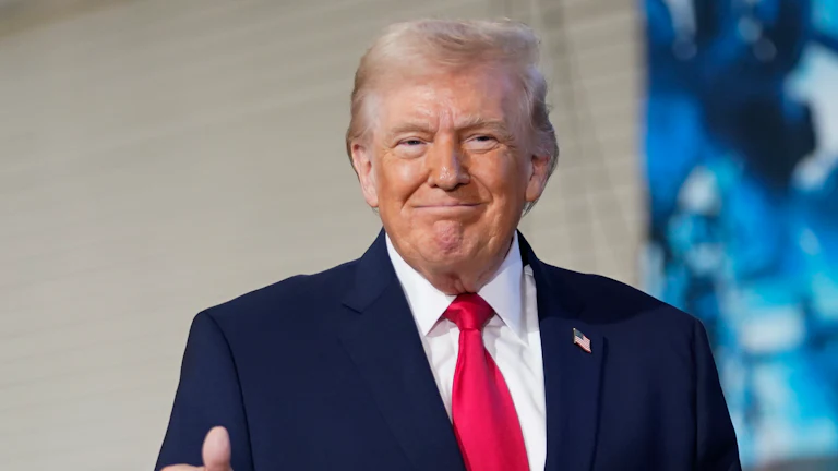 Donald Trump smiles while making a "thumbs up" sign.