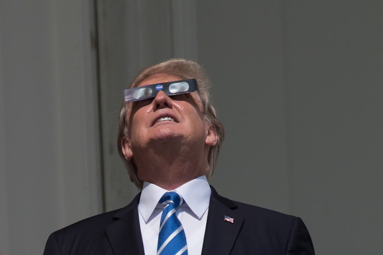 Donald Trump wears eclipse glasses and stares into the sun