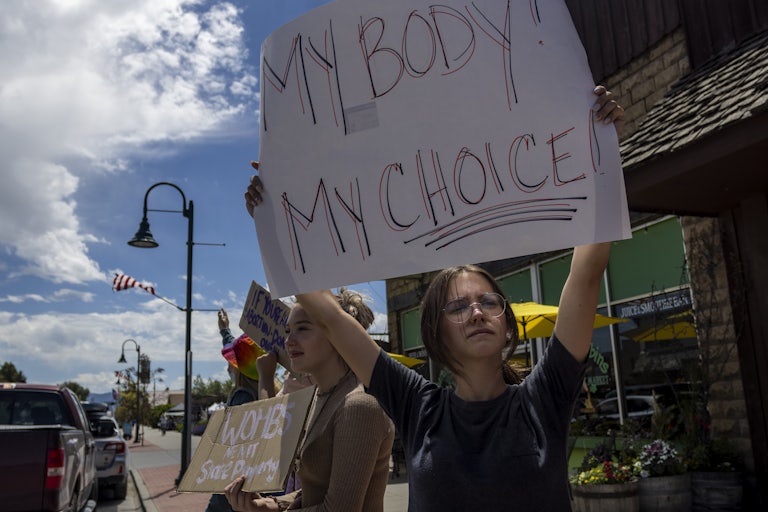 A teenage girl in the foreground holds a sign that reads "My Body My Choice!" Another in the background holds a sign that says "Wombs Are Not State Property."