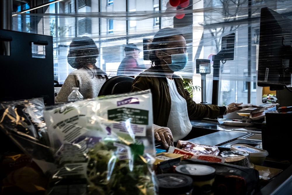 A cashier works wearing a face mask in a supermarket in Givors, near Lyon