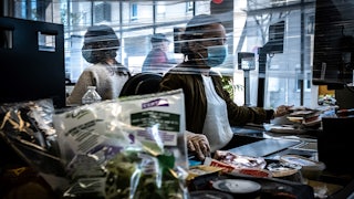A cashier works wearing a face mask in a supermarket in Givors, near Lyon