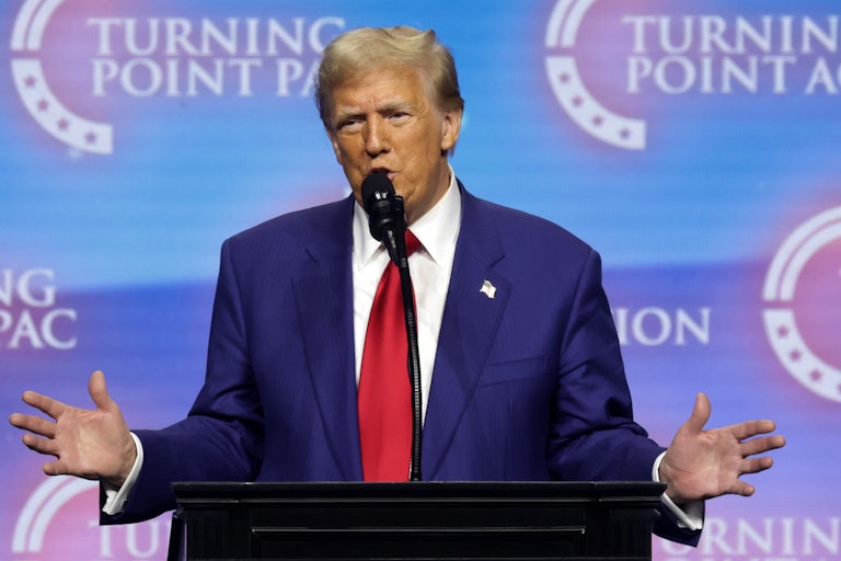 Donald Trump holds his hands out while speaking at a podium during a campaign event
