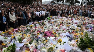 People stand next to a memorial for shooting victims at Bondi Beach