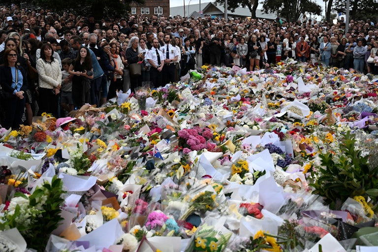 People stand next to a memorial for shooting victims at Bondi Beach