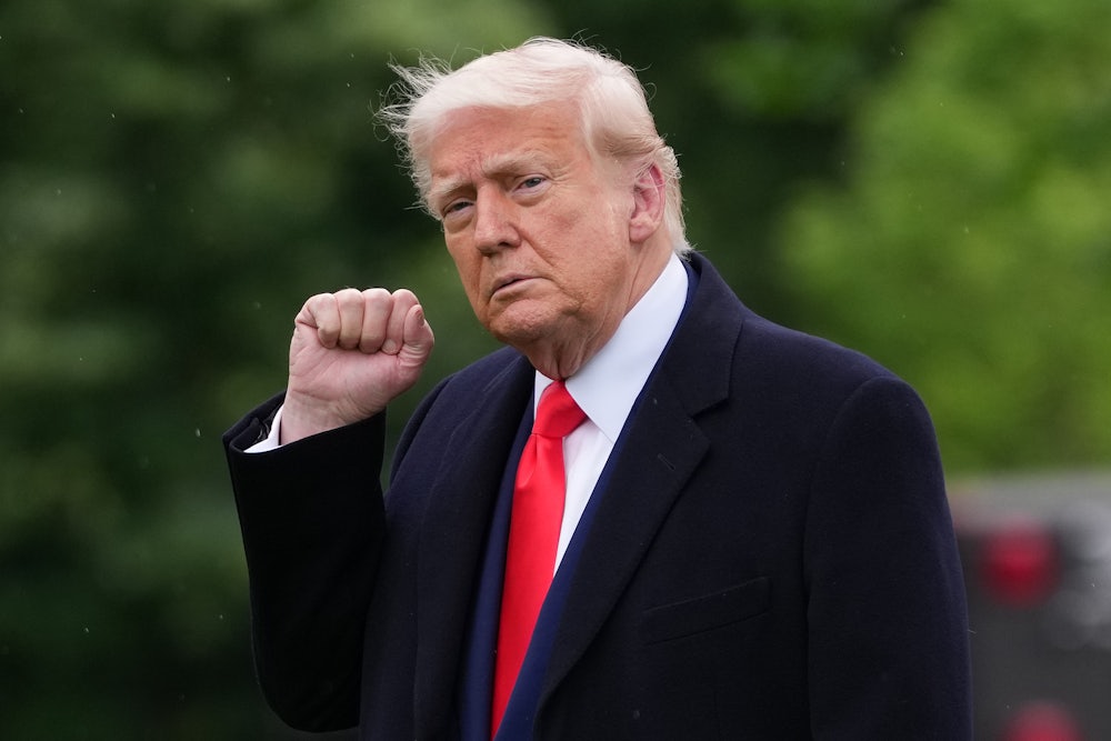 Donald Trump raises his fist while walking outside the White House