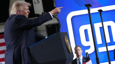 Donald Trump points while speaking behind a podium.