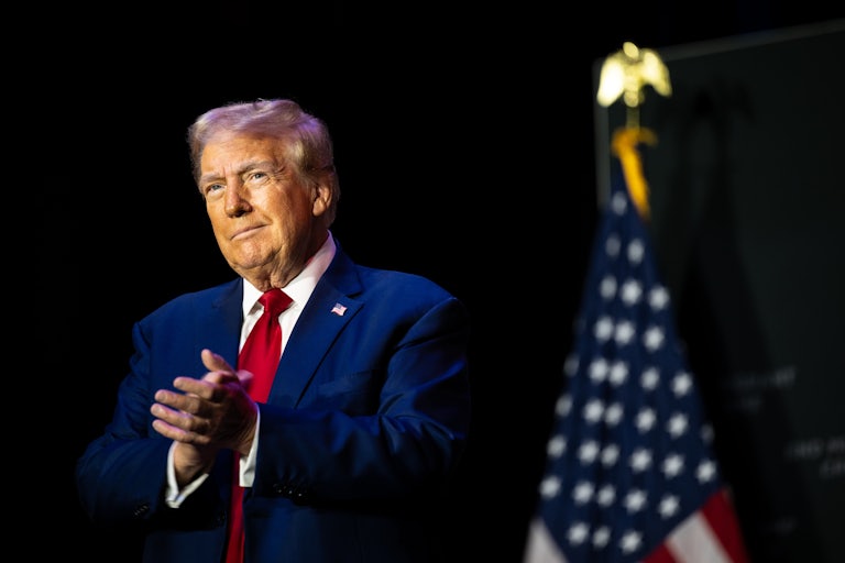 Donald Trump smiles slightly and claps
