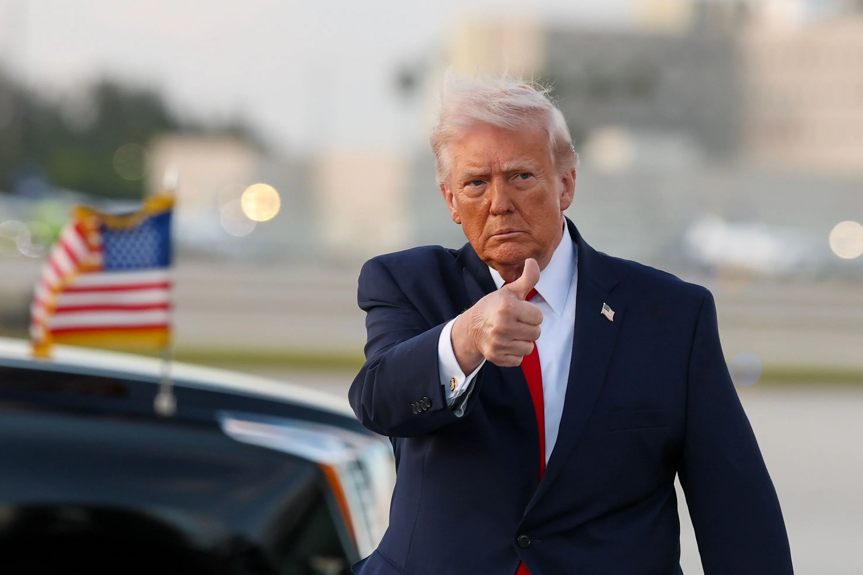 Donald Trump gives a thumbs-up while walking on an airport tarmac