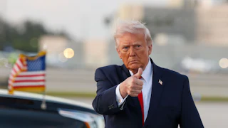 Donald Trump gives a thumbs-up while walking on an airport tarmac