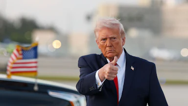 Donald Trump gives a thumbs-up while walking on an airport tarmac
