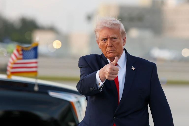 Donald Trump gives a thumbs-up while walking on an airport tarmac