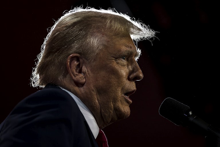 Donald Trump in profile speaking vehemently into a microphone