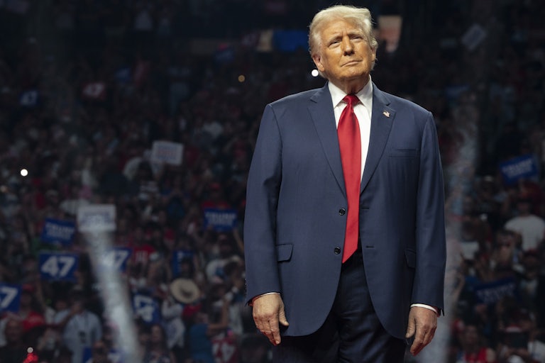 Donald Trump stands and smiles at a campaign rally