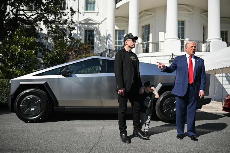 Donald Trump and Elon Musk stand in front of a Tesla Cybertruck on the South Lawn of the White House. Trump points at Musk and speaks, while Musk zones out.