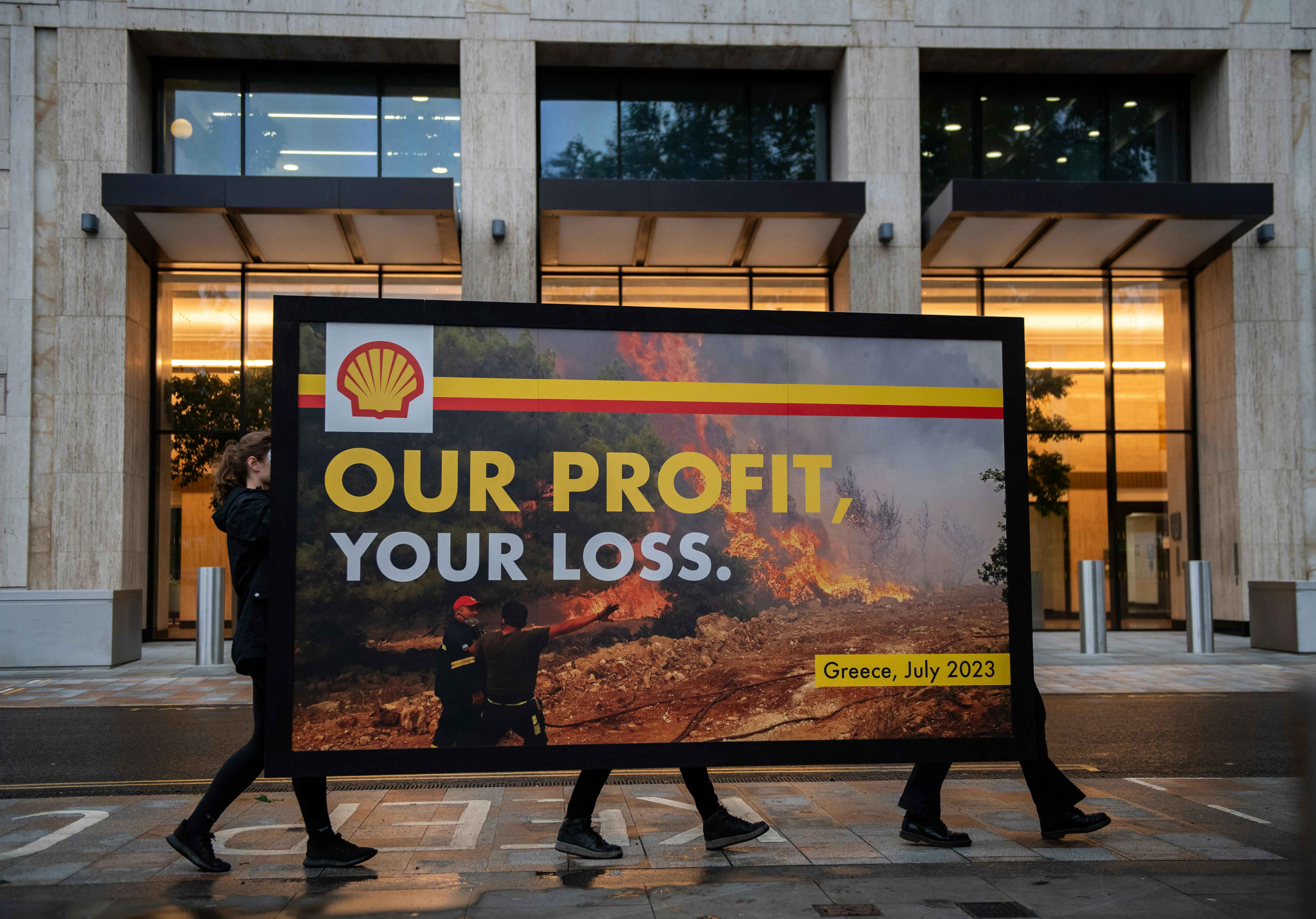 Greenpeace activists hold a billboard during a protest outside Shell headquarters